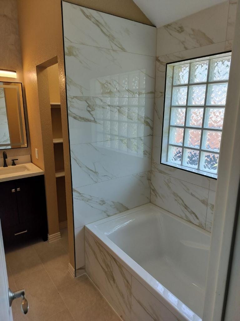 The newly remodeled bathroom has a luxurious bathtub and marble tile walls.