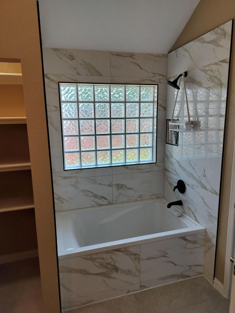 The remodeled bathroom features a spacious tub and a large glass block window.