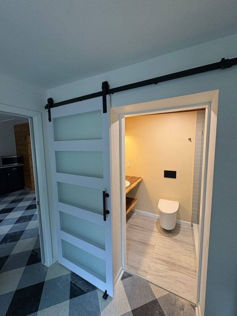 Frosted glass sliding door open to modern bathroom with warm lighting