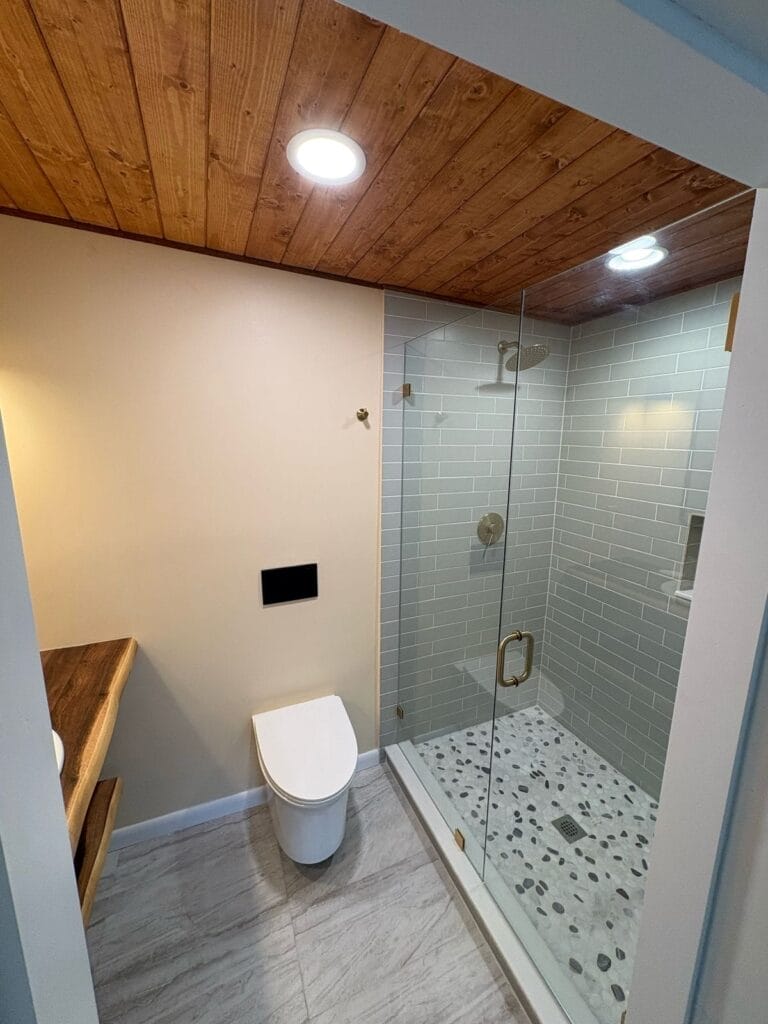 Shower with gray subway tile, glass door, and wood ceiling