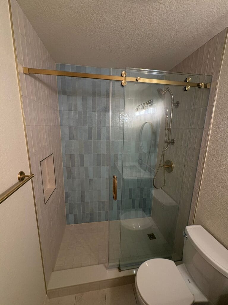 Gold barn-door style sliding shower doors and vertical tile pattern