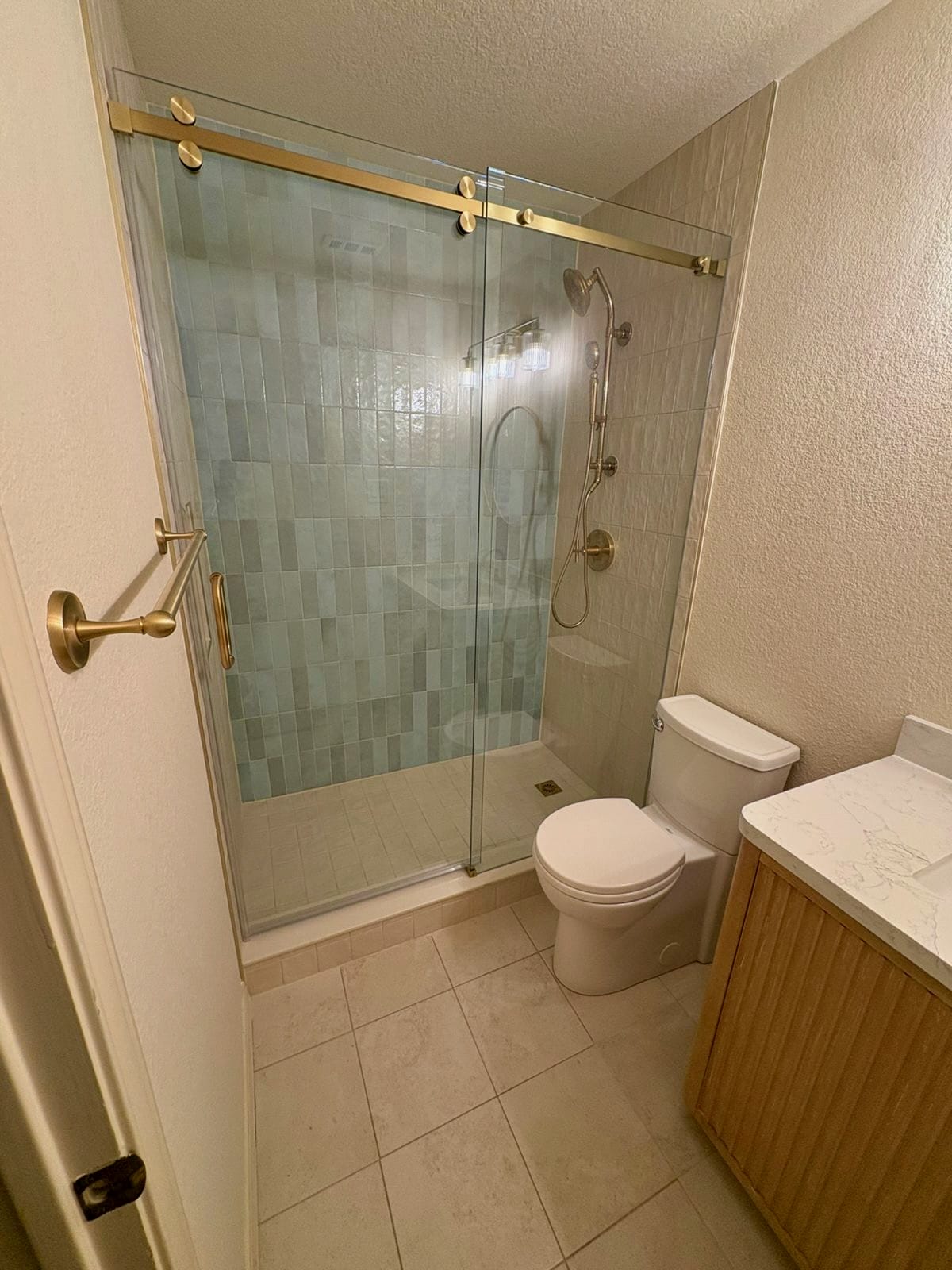 Bathroom with gold barn-door style sliding shower doors and vertical tile pattern