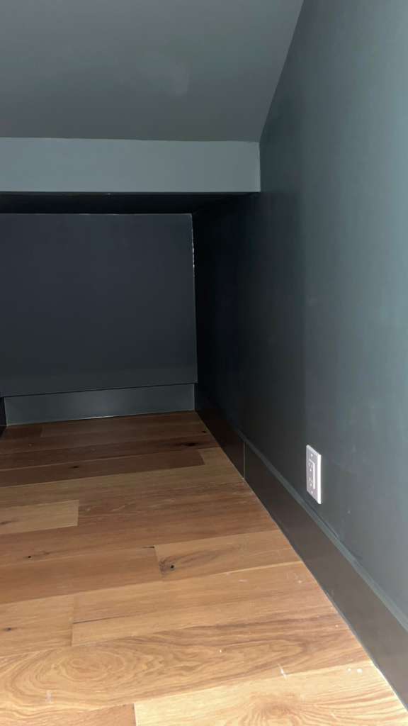 Dark painted interior of custom under-stair closet before cabinet door installation