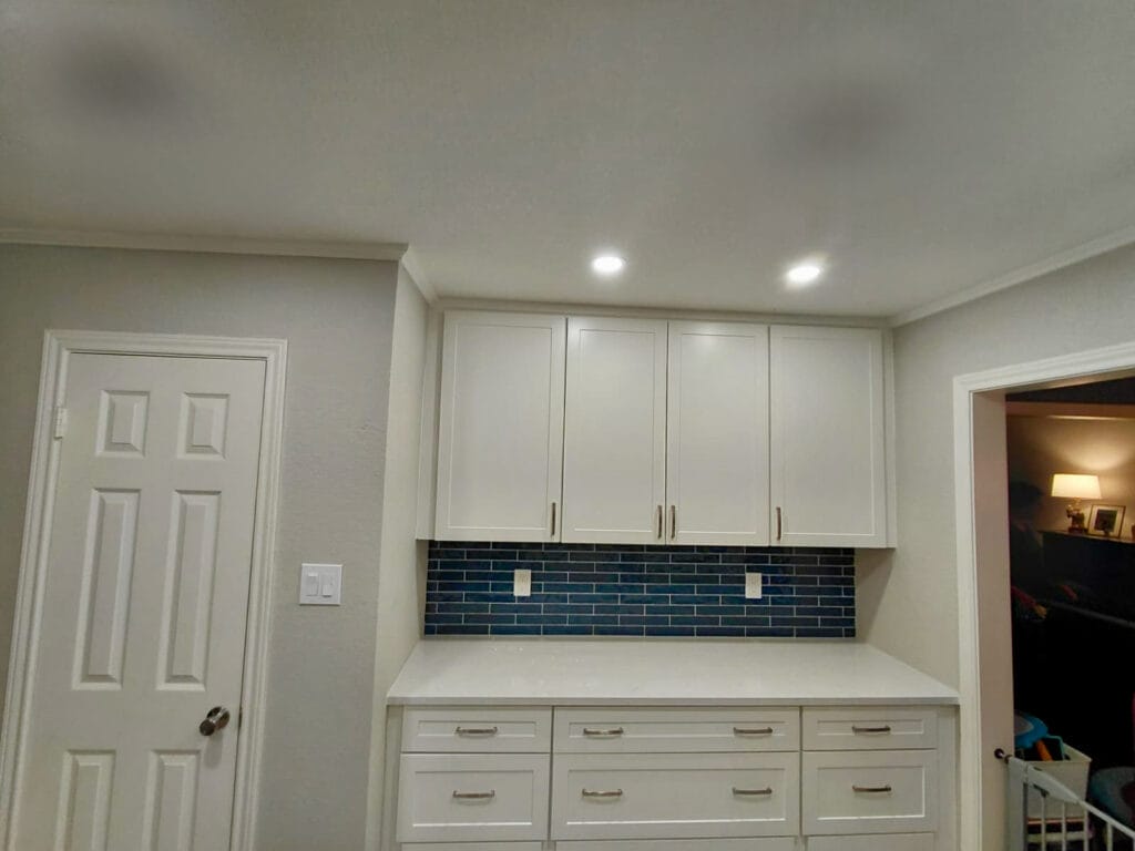 White shaker cabinets with blue subway tile backsplash and white quartz countertops in an Austin kitchen remodel
