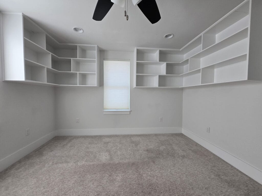 White floating shelves with asymmetrical cubbies wrapping two walls in a family room