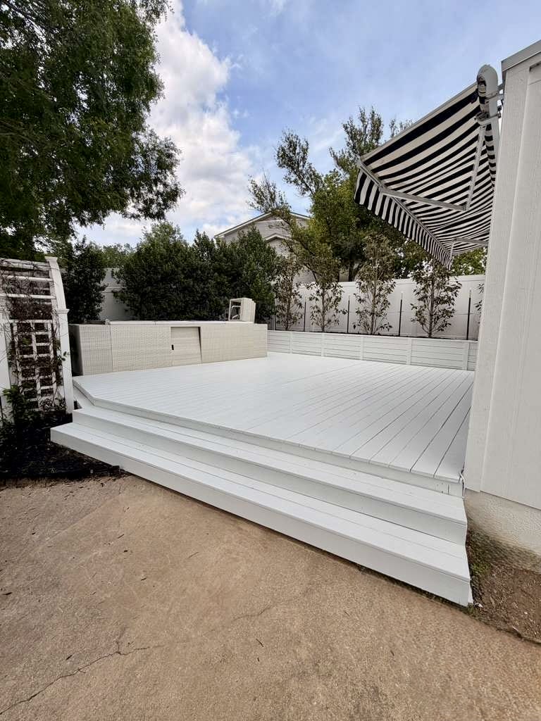 Finished backyard deck painted solid white with retractable striped awning in Austin