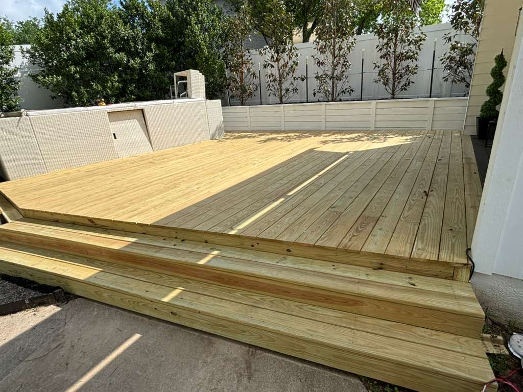 Newly built pressure-treated lumber deck with wide steps in an Austin backyard, before painting